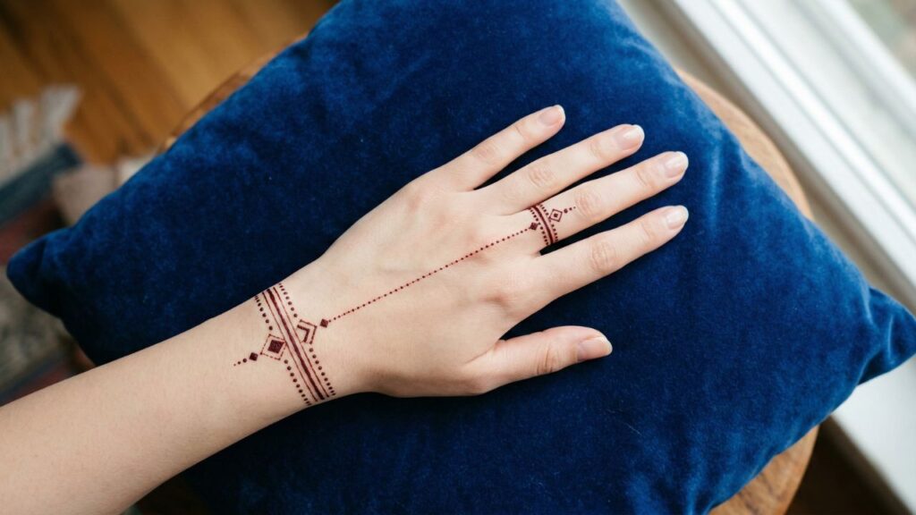 Top view of a modern jewelry mehndi design connecting a minimalist wrist cuff to a finger ring.